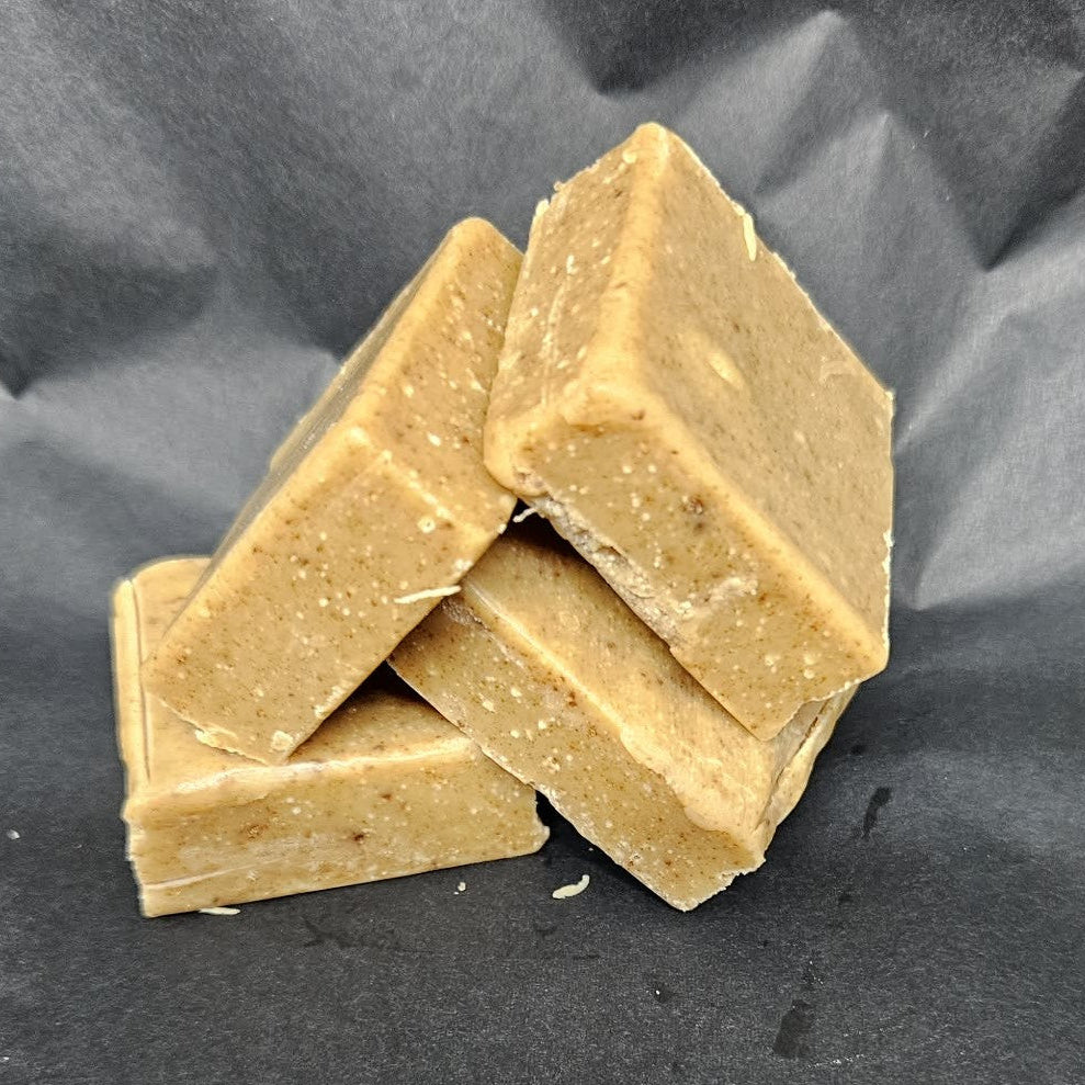 Four square bars of fudge stacked on a dark gray background