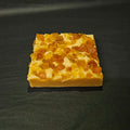 Square piece of fudge
 with a textured surface on a dark background