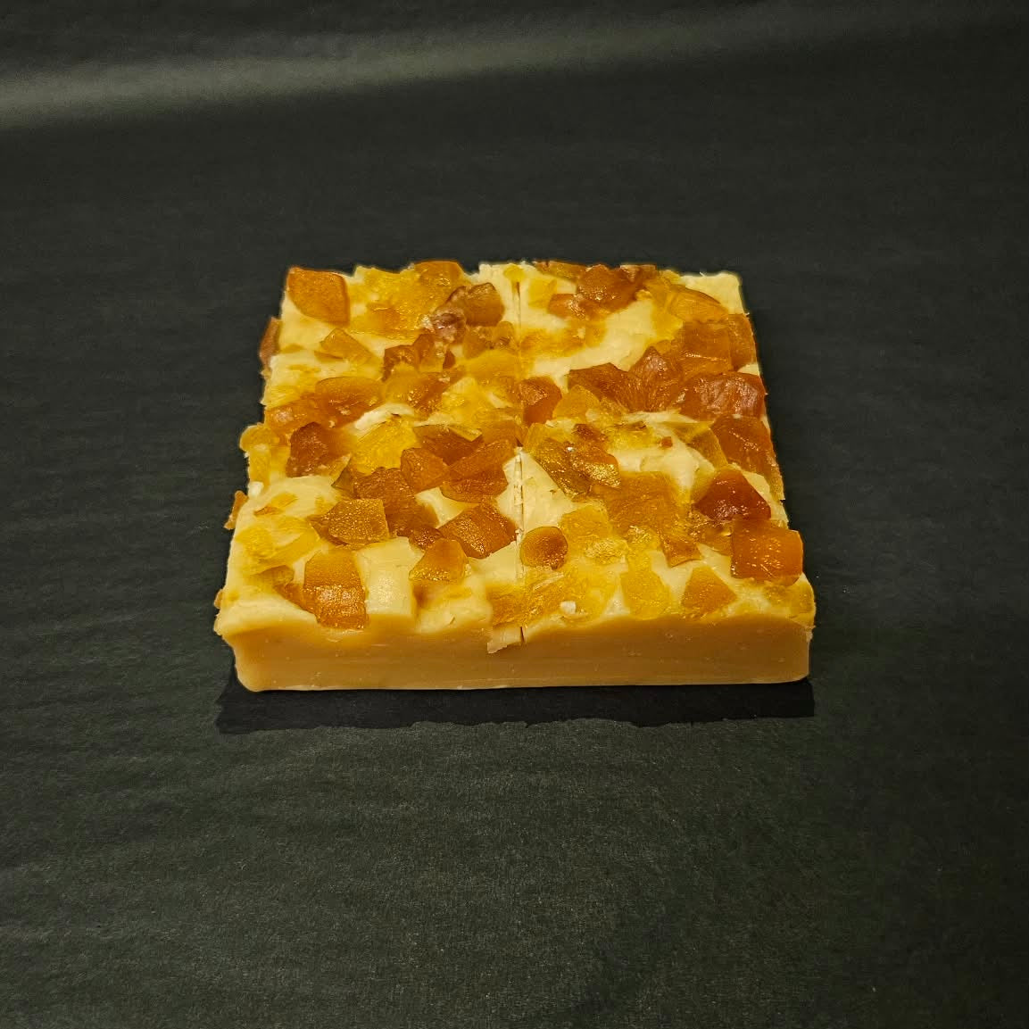 Square piece of fudge
 with a textured surface on a dark background