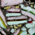Layered dessert with pink, green, and white colors on a dark background