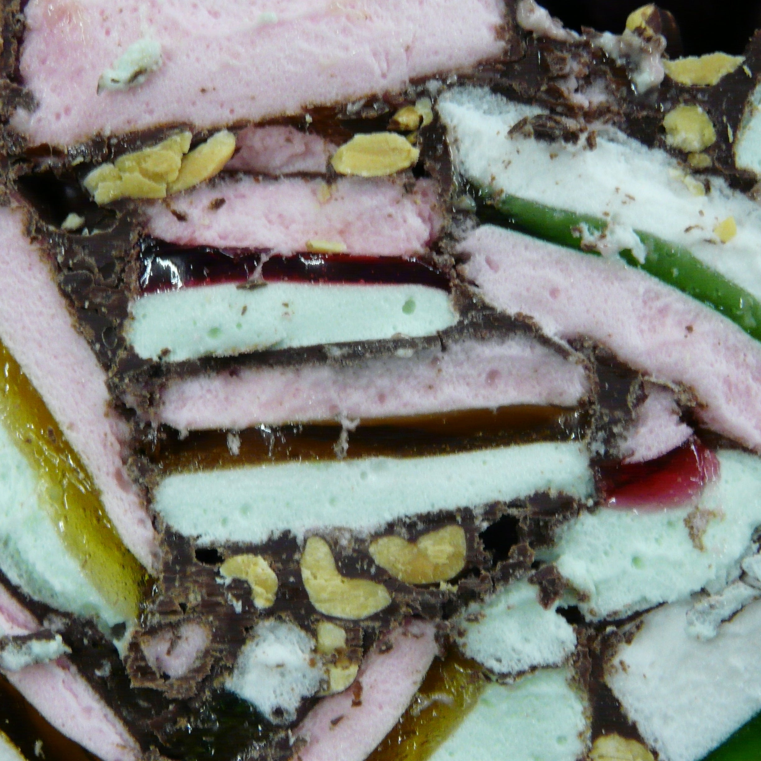 Layered dessert with pink, green, and white colors on a dark background