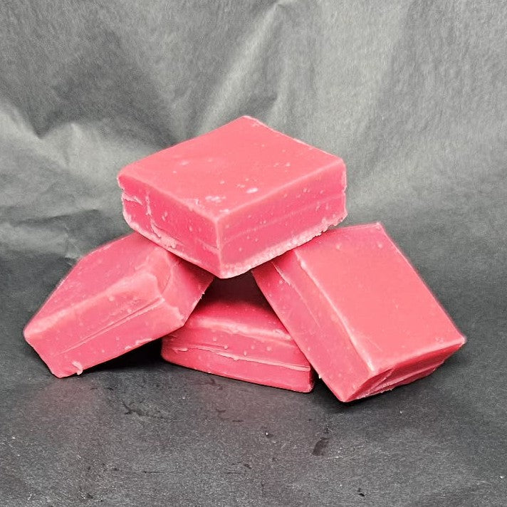 Pink fudge bars stacked on a gray fabric background