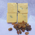 Four blocks of fudge with raisins on a light purple background