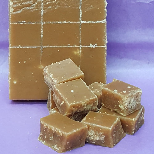 Block of caramel fudge with pieces on a purple background