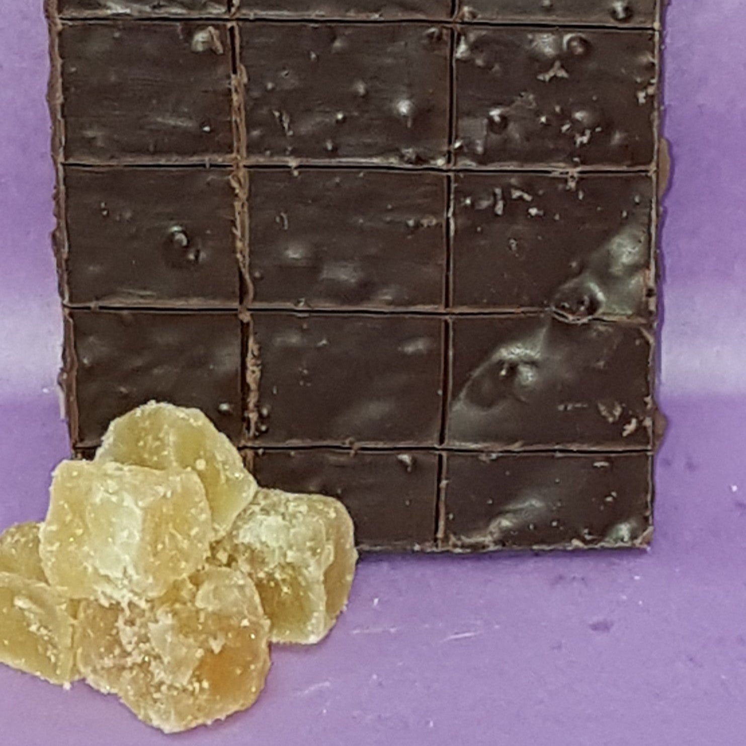 Dark chocolate bar with a crumbly texture on a purple background