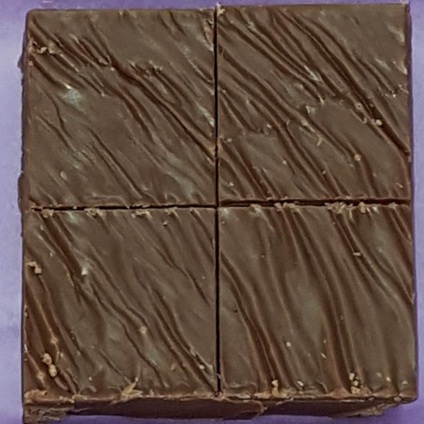 Chocolate bar cut into four pieces on a purple background
